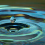 water drop falling and impacting on a body of water close up